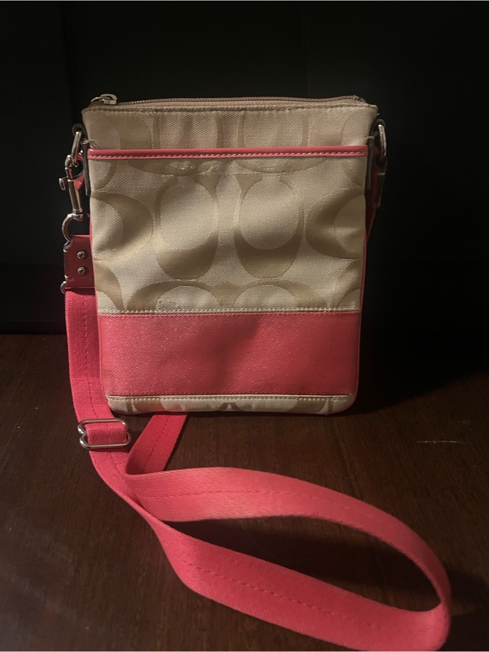 Coach signature canvas crossbody with coral pink accents.